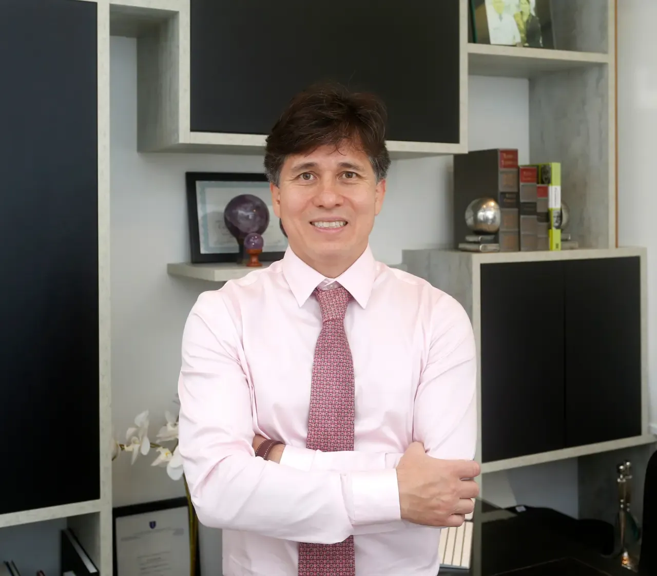 Dr. Rafael Higashi de braços cruzados no consultório da Clínica Higashi